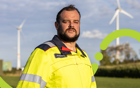 Voor de netwerken voor morgen Technieker van Fluvius met een windmolen op de achtergrond